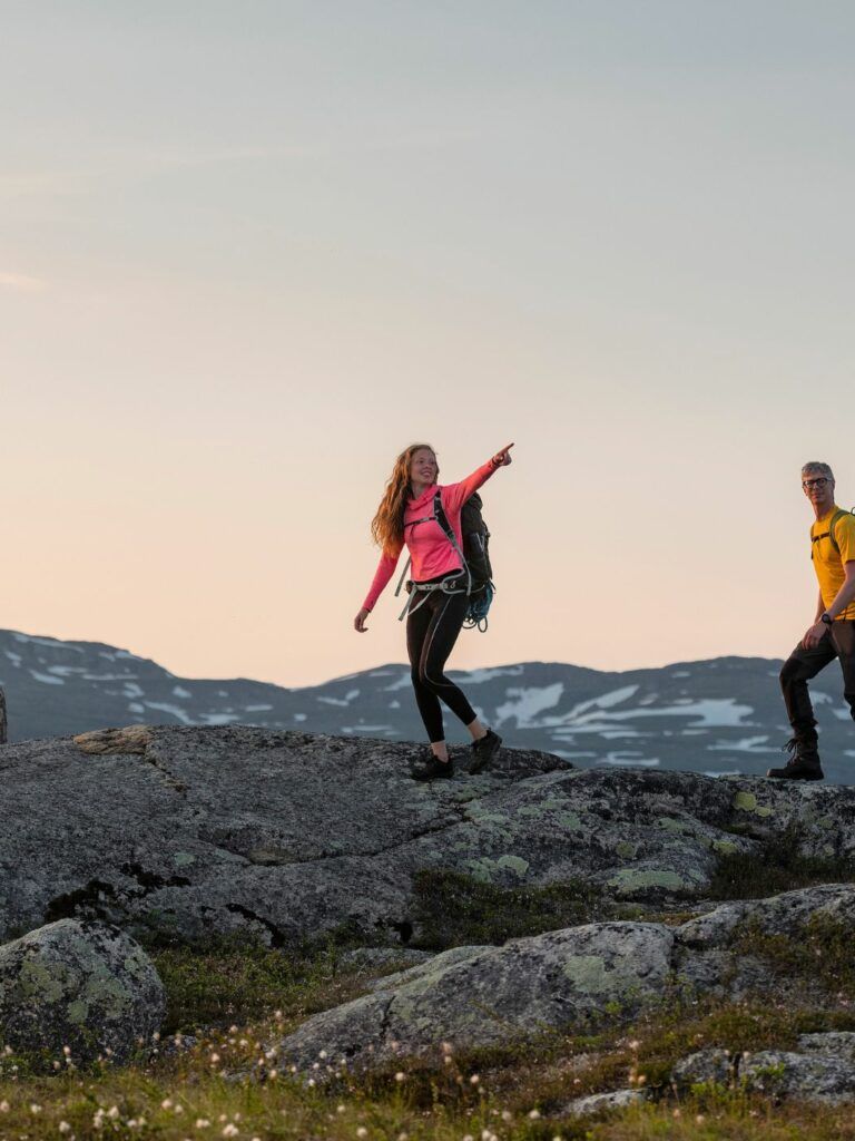 Två perspner vandrar i fjällmiljö. Den ena personen pekar mot något i fjärran.