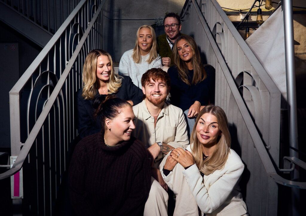 Fem kollegor från Oddwork sitter i en trappa.